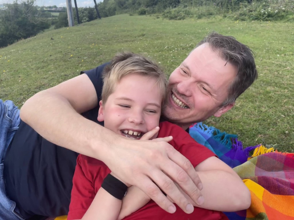 Anthony hugging a smiling child on a picnic blanket outdoors